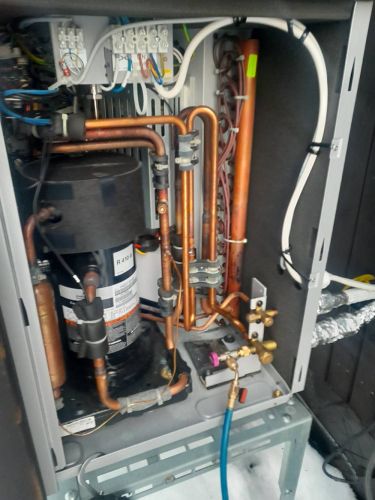 Ilmavesilämpöpumpun kaapin sisältä. Paljon kupariputkea ja sähköjohtoja.